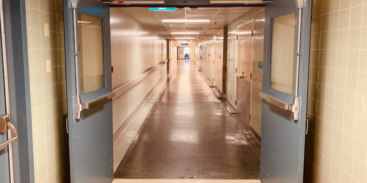 Hospital doors open to reveal a long corridor